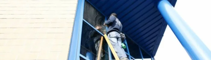 Glazenwasser van Boons Bockx aan het werk op een ladder aan een glazen gevel